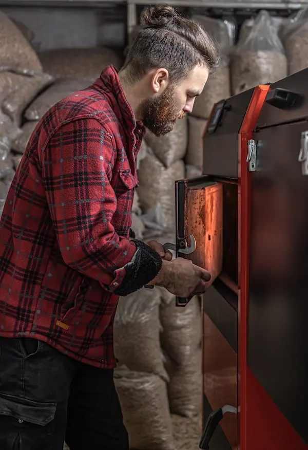 un homme dans une piece avec une chaudiere a combustible solide travaillant au biocarburant chauffage economique un homme dans une piece avec une chaudiere a combustible solide travaillant au biocarburant chauffage economique